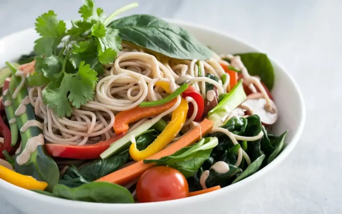 A vibrant bowl of healthy noodles with fresh vegetables and herbs