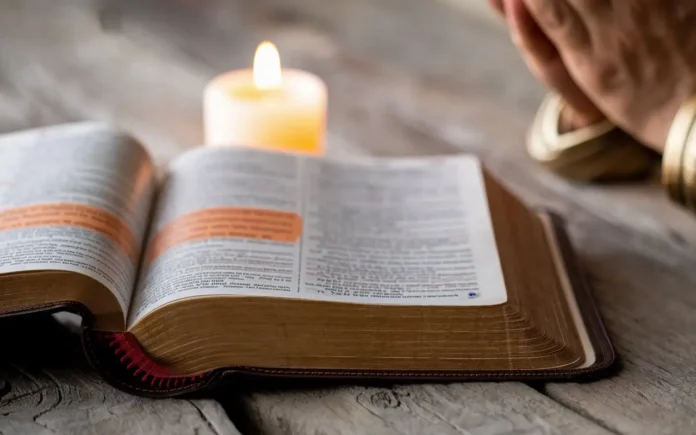 A serene image of a Bible, open to a fasting and prayer verse, placed on a wooden table with a lit candle beside it.