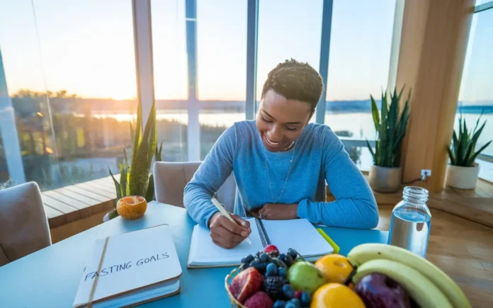 A person looking motivated while journaling their fasting journey, with a serene sunrise background to represent inspiration.