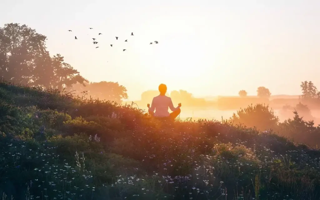 A serene sunrise with a figure meditating, symbolizing spiritual clarity and benefits of fasting.