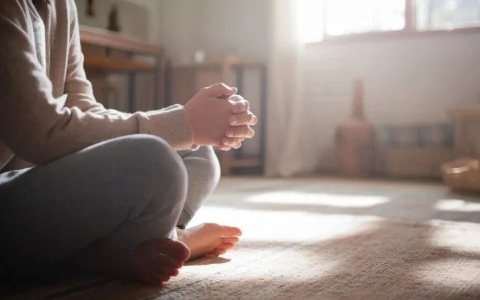 A serene individual praying with closed eyes during a fasting period