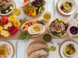 A colorful spread of Mediterranean vegetarian foods, including fresh vegetables, legumes, olive oil, and whole grains.