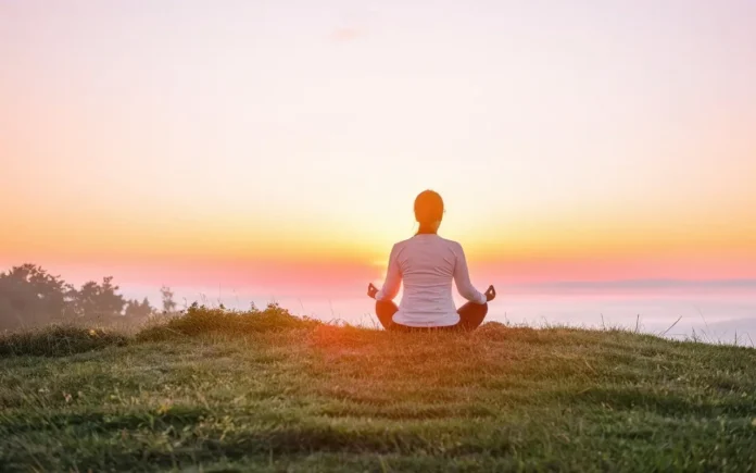 A serene image of a person meditating outdoors during sunrise, symbolizing spiritual fasting and inner peace.